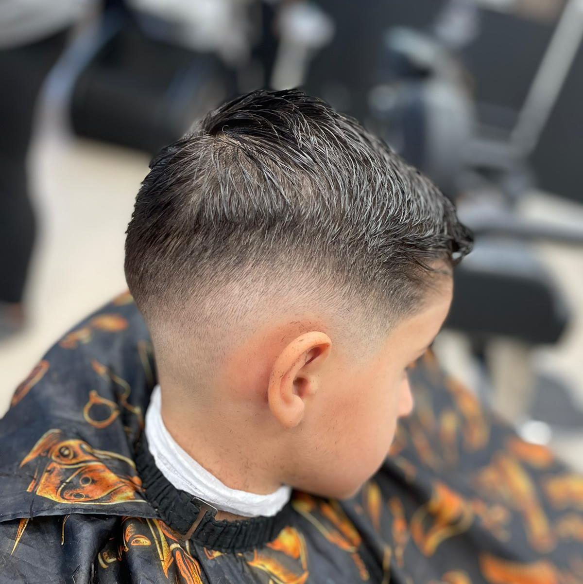 Jongen met een mid fade, van opzij in de kappersstoel